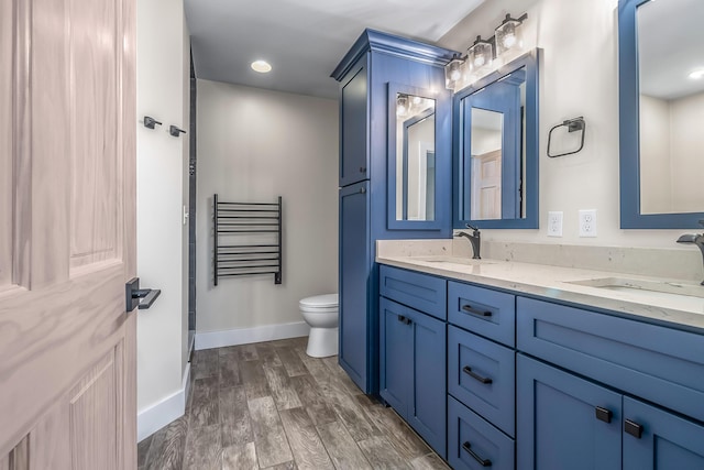 full bath featuring baseboards, toilet, double vanity, and wood finished floors