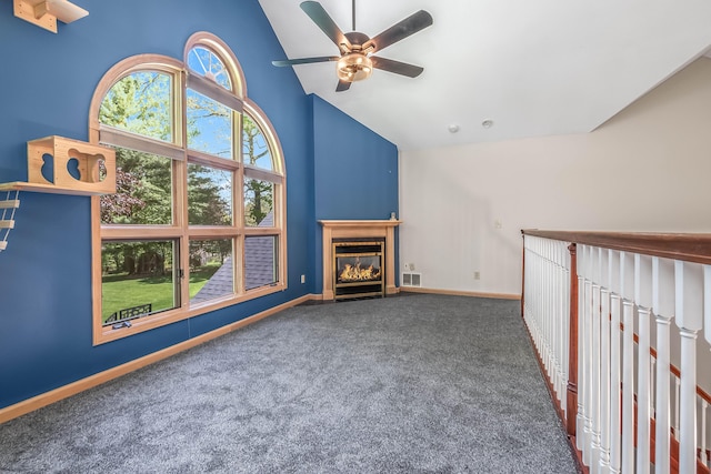 unfurnished living room with carpet flooring, high vaulted ceiling, ceiling fan, baseboards, and a glass covered fireplace
