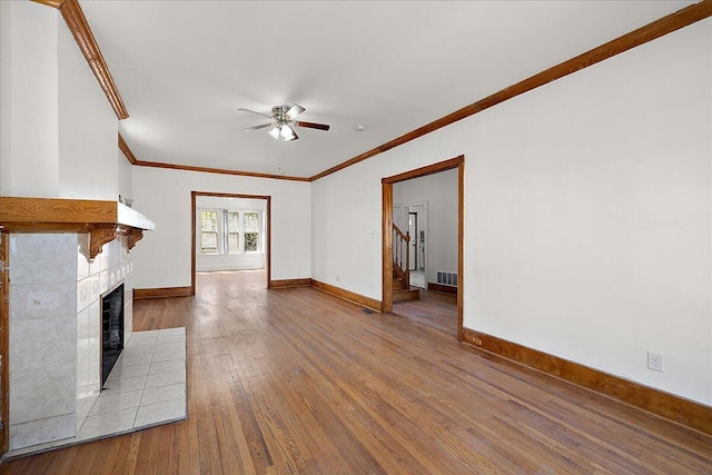 1199 Atkinson St, Detroit, MI 48202 - unfurnished living room with ornamental molding, a ceiling fan, a tiled fireplace, wood-type flooring, and baseboards