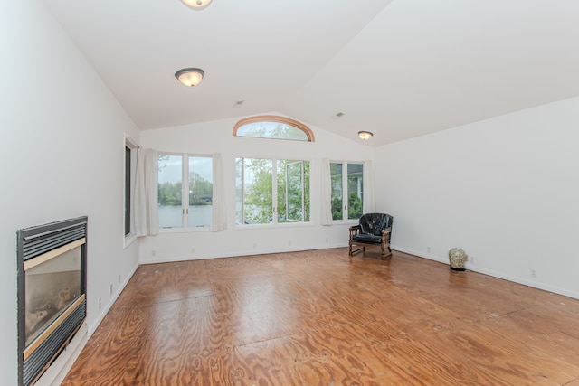 unfurnished living room with a glass covered fireplace, wood finished floors, and lofted ceiling