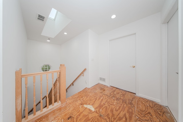 corridor featuring a skylight, an upstairs landing, and recessed lighting