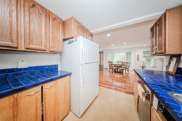 kitchen with freestanding refrigerator, recessed lighting, dishwasher, tile counters, and light flooring