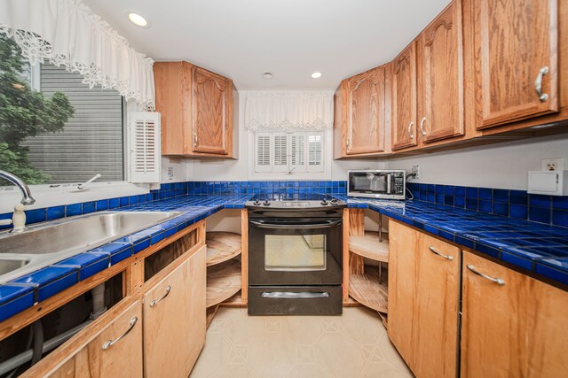 kitchen with electric range, stainless steel microwave, a sink, recessed lighting, and tile countertops