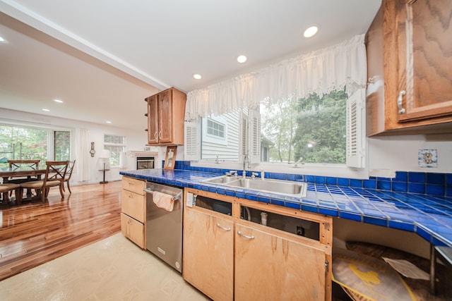 kitchen featuring dishwasher, a sink, recessed lighting, and tile counters