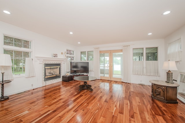 unfurnished living room with light wood-style floors, french doors, a glass covered fireplace, and recessed lighting