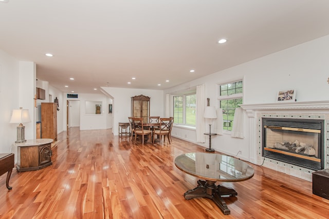 living room featuring light wood-style flooring, a tile fireplace, and recessed lighting