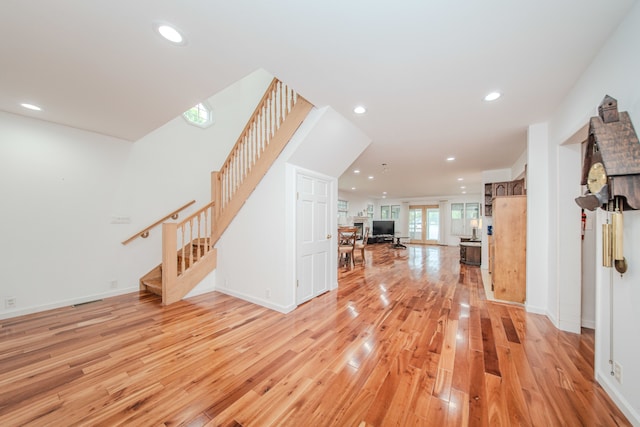 unfurnished living room with stairway, light wood finished floors, recessed lighting, and baseboards