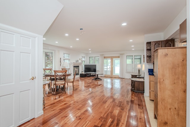 living area featuring light wood-style floors, recessed lighting, and a glass covered fireplace