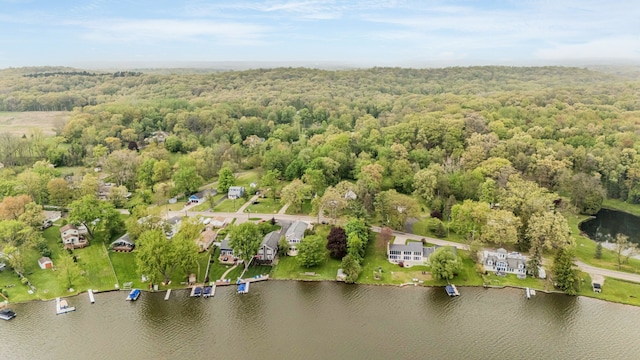 aerial view of property and surrounding area featuring a heavily wooded area and a large body of water