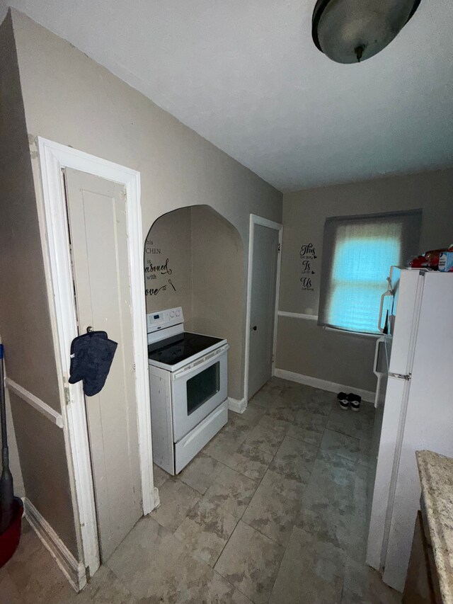 kitchen featuring white appliances, light countertops, and baseboards