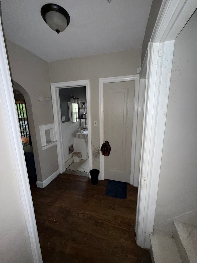 hallway with wood finished floors and arched walkways