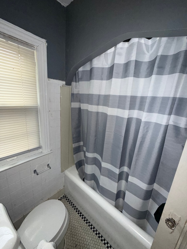 bathroom featuring tile walls, tile patterned floors, toilet, and shower / tub combo