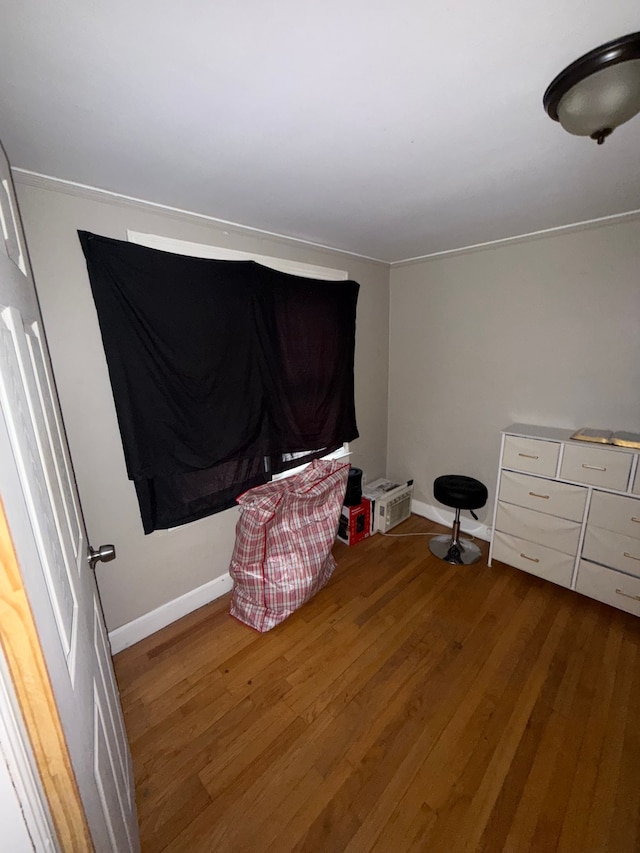 bedroom with wood finished floors, baseboards, and crown molding