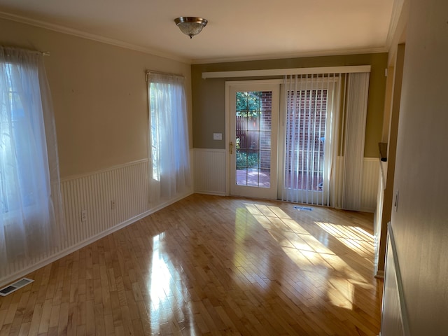 spare room with wainscoting, wood-type flooring, and crown molding