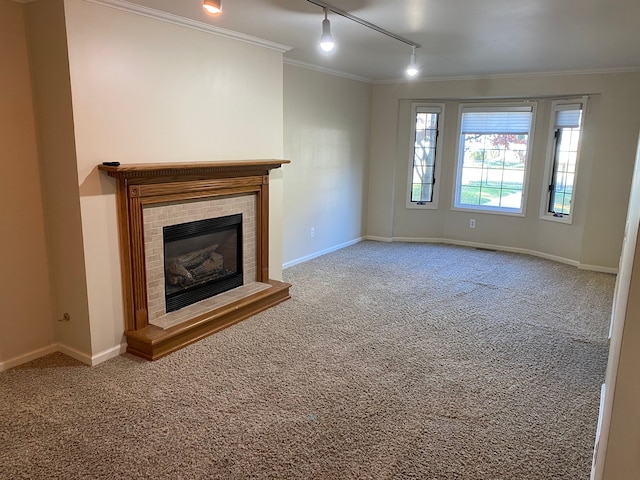 unfurnished living room featuring rail lighting, carpet flooring, ornamental molding, a fireplace, and baseboards