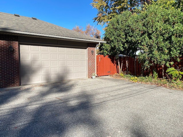 garage with fence and asphalt driveway