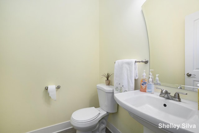 2496 Wolf Lake Dr, Baldwin, MI 49304 - half bathroom featuring a sink, toilet, and baseboards