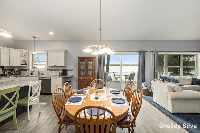 2496 Wolf Lake Dr, Baldwin, MI 49304 - dining room with a chandelier, light wood-style flooring, a water view, and recessed lighting