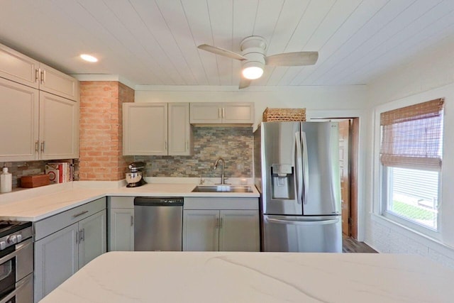 kitchen with stainless steel appliances, a sink, gray cabinetry, tasteful backsplash, and a ceiling fan