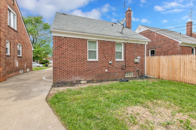 back of property featuring brick siding, roof with shingles, and a chimney
