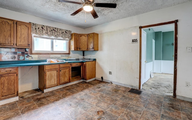 156 W 19th St, Holland, MI 49423 - kitchen featuring brown cabinets, ceiling fan, a textured ceiling, baseboards, and dark stone finish floors
