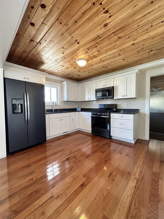 12061 Emelia St, Birch Run, MI 48415 - kitchen with black appliances, dark countertops, wood-type flooring, white cabinets, and wood ceiling