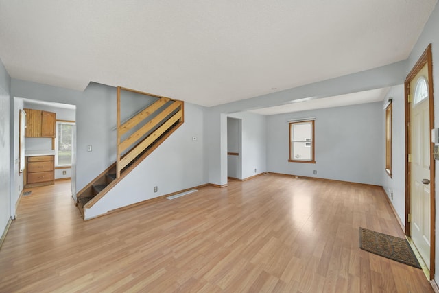 5732 Selfridge Blvd, Lansing, MI 48911 - unfurnished living room with stairs, light wood finished floors, healthy amount of natural light, and baseboards