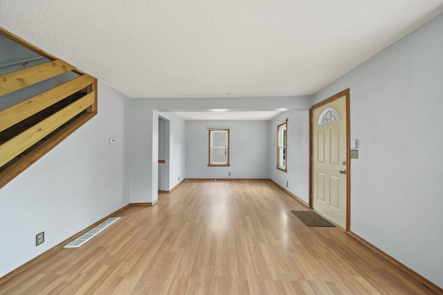 5732 Selfridge Blvd, Lansing, MI 48911 - unfurnished living room featuring light wood-type flooring, a textured ceiling, and baseboards