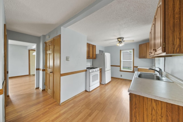 5732 Selfridge Blvd, Lansing, MI 48911 - kitchen featuring white appliances, a sink, a textured ceiling, light wood-type flooring, and brown cabinets