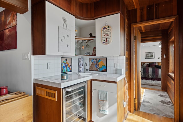 9417 Cedar Island Rd, White Lake, MI 48386 - indoor wet bar featuring beverage cooler, decorative backsplash, a ceiling fan, and light wood finished floors