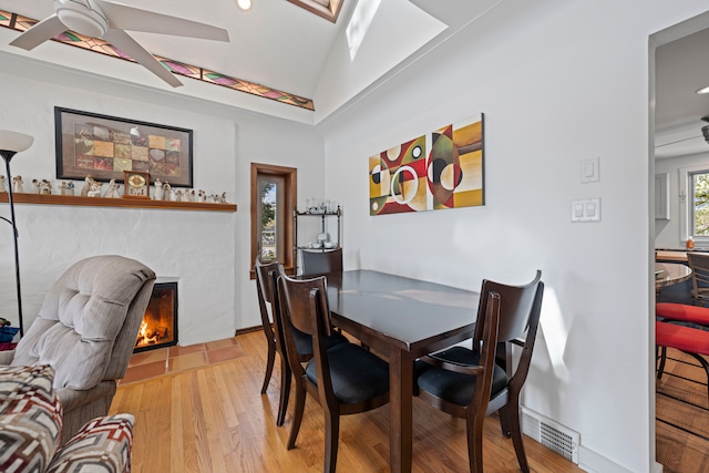9417 Cedar Island Rd, White Lake, MI 48386 - dining room featuring light wood-style flooring, a fireplace with flush hearth, a ceiling fan, recessed lighting, and vaulted ceiling