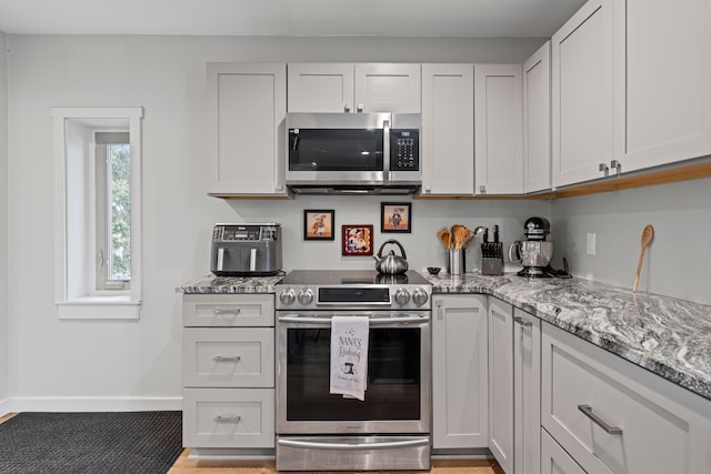 9417 Cedar Island Rd, White Lake, MI 48386 - kitchen featuring stainless steel appliances, baseboards, and light stone countertops