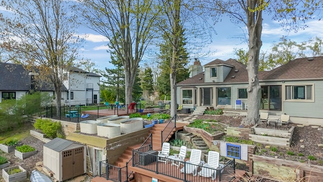 9417 Cedar Island Rd, White Lake, MI 48386 - rear view of house with a garden, a storage unit, and fence