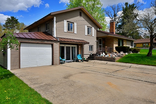 9609 E Madison Rd, Saint Helen, MI 48656 - tri-level home with a garage, concrete driveway, a standing seam roof, metal roof, and a front lawn