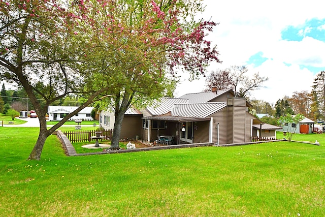 9609 E Madison Rd, Saint Helen, MI 48656 - back of house featuring a standing seam roof, a yard, metal roof, and a chimney