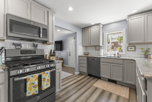 22171 Monterey Dr, Trenton, MI 48183 - kitchen with stainless steel appliances, a sink, tasteful backsplash, light wood-type flooring, and recessed lighting