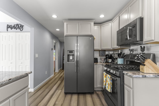 22171 Monterey Dr, Trenton, MI 48183 - kitchen featuring appliances with stainless steel finishes, light wood finished floors, recessed lighting, backsplash, and light stone counters
