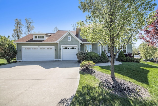 view of front of house featuring an attached garage, driveway, a front lawn, and a shingled roof