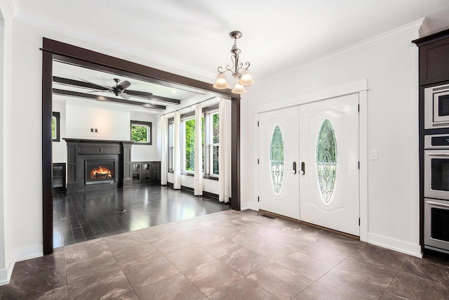 8030 Lionel Dr SW, Byron Center, MI 49315 - entrance foyer featuring a chandelier, beamed ceiling, crown molding, a warm lit fireplace, and dark tile patterned floors
