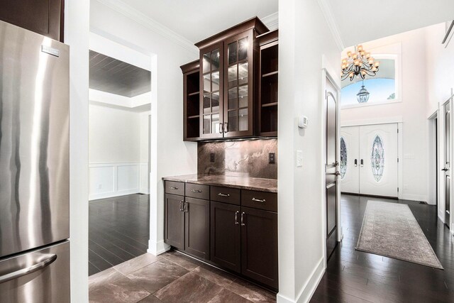 8030 Lionel Dr SW, Byron Center, MI 49315 - kitchen featuring freestanding refrigerator, dark brown cabinetry, a chandelier, crown molding, and glass insert cabinets