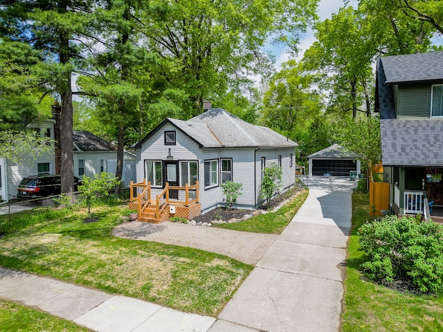 bungalow-style home with an outbuilding, a garage, a shingled roof, and a chimney