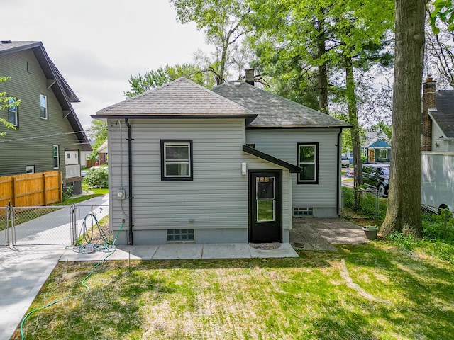 rear view of property with a gate, a patio area, and roof with shingles