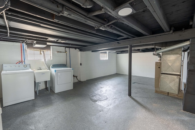 basement featuring washing machine and clothes dryer and a sink
