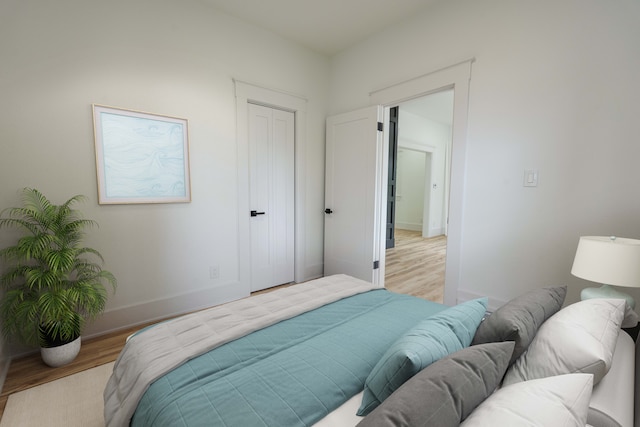 bedroom featuring light wood-style flooring, baseboards, and a closet