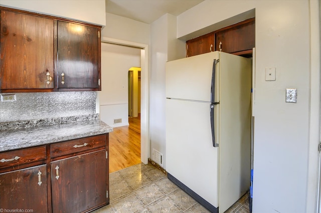 kitchen featuring freestanding refrigerator, arched walkways, and light countertops