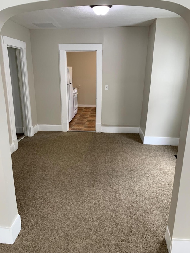 954 Adams St SE, Grand Rapids, MI 49507 - unfurnished room featuring arched walkways, dark colored carpet, and baseboards