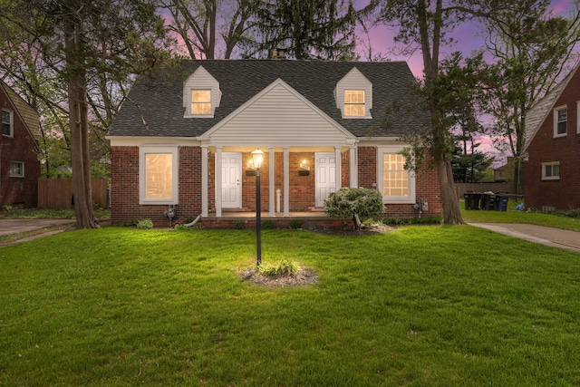 7407 Curtis St, Detroit, MI 48221 - cape cod house featuring brick siding, covered porch, and roof with shingles
