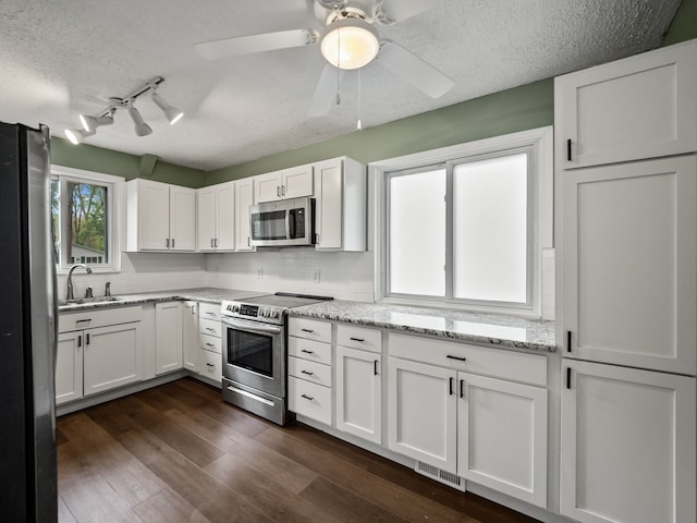 21357 Poinciana St, Southfield, MI 48033 - kitchen featuring appliances with stainless steel finishes, a sink, white cabinetry, backsplash, and a textured ceiling