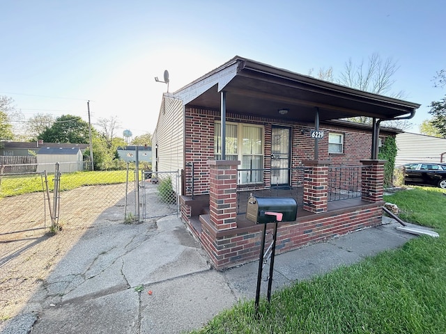 view of front of house with brick siding, a gate, a porch, and fence