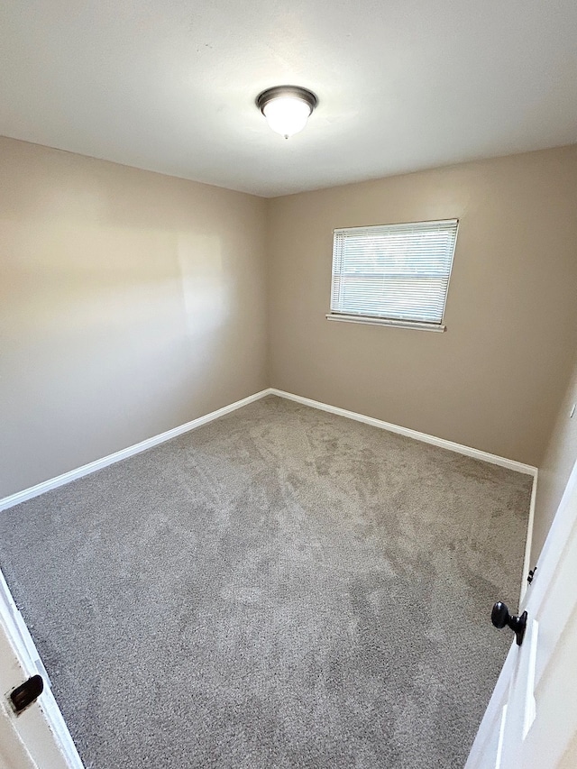 unfurnished room featuring carpet and baseboards